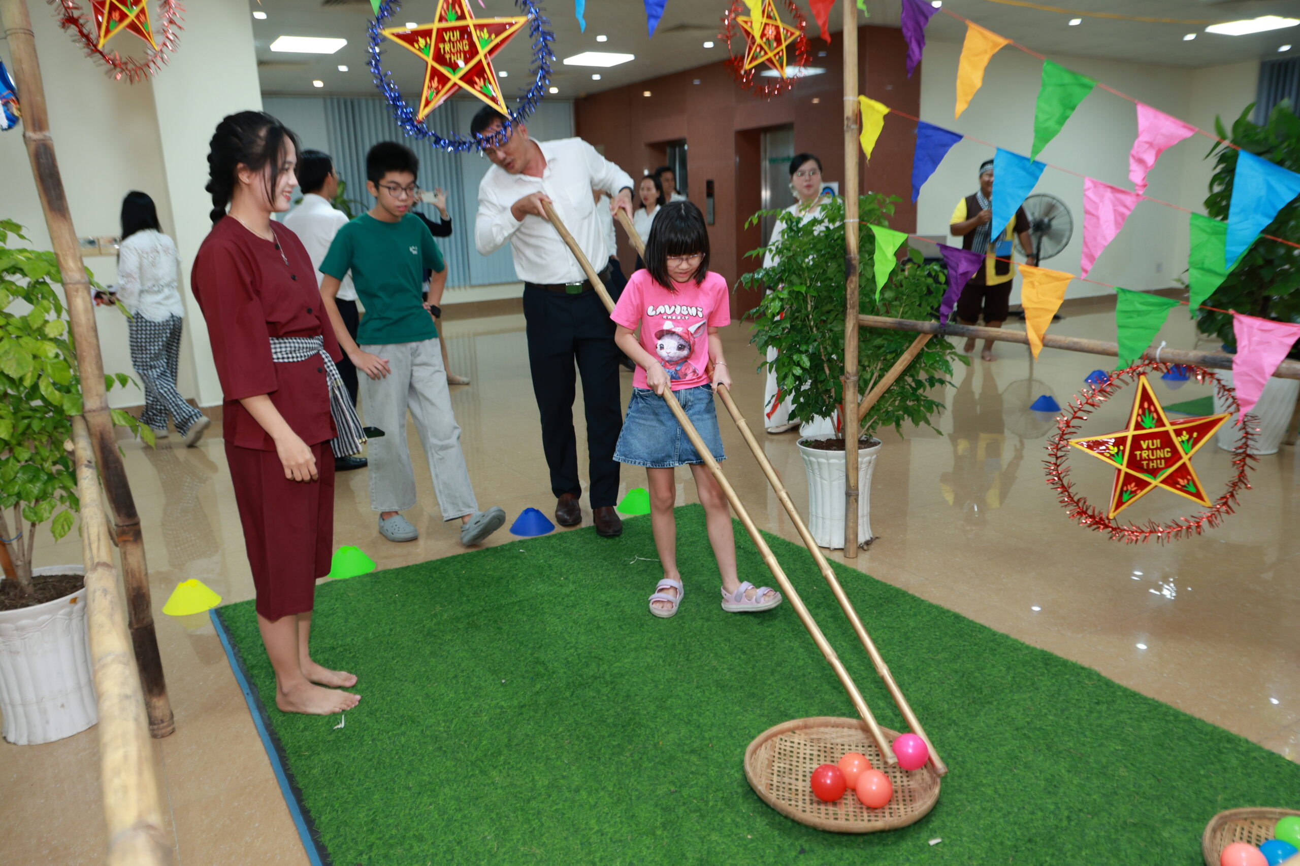 Bé gái dùng đôi đũa tre khổng lồ gắp quả cầu trăng vào nia tre
