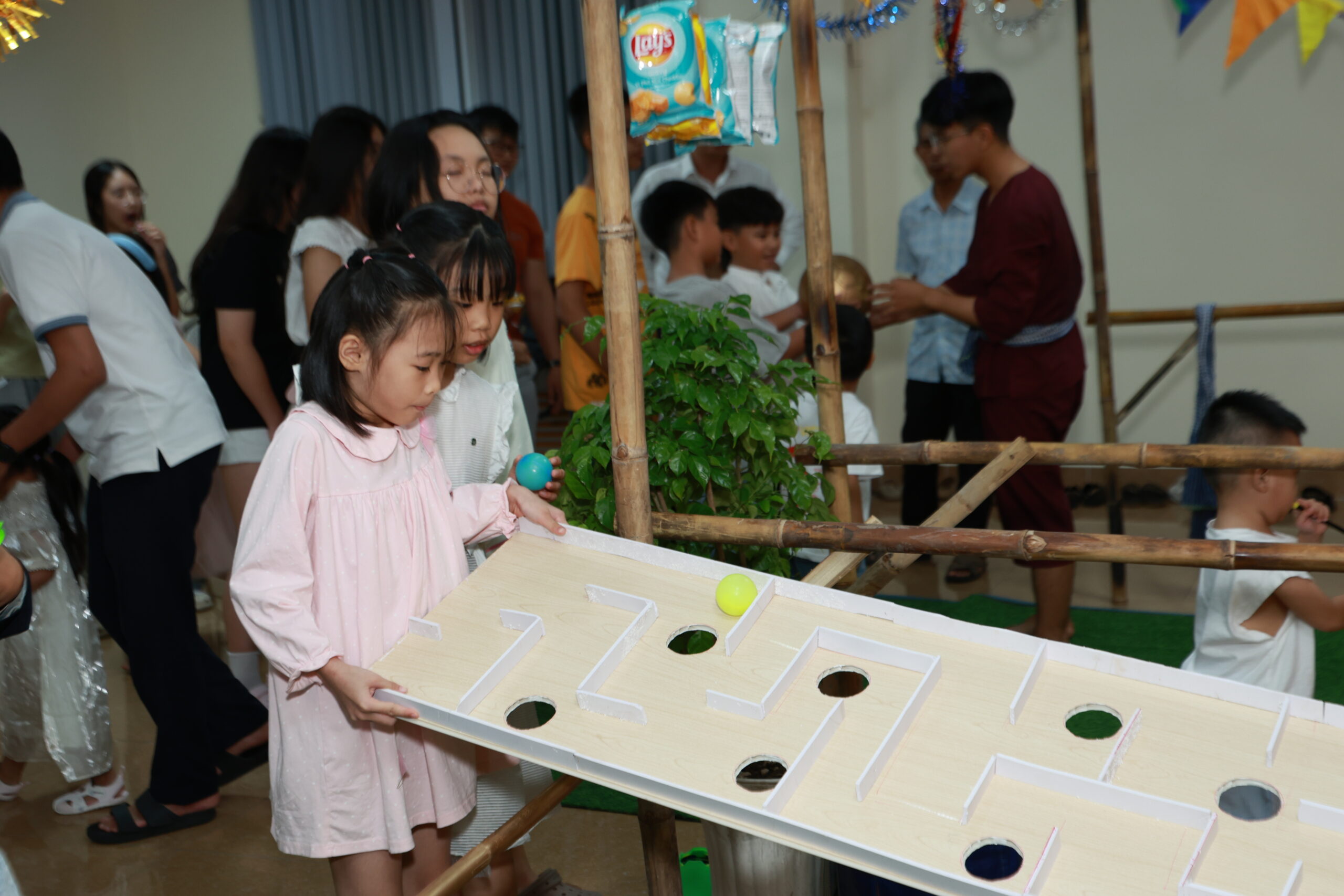Bé gái tập trung cao độ khéo léo nghiêng khay gỗ mê cung điều khiển quả bóng