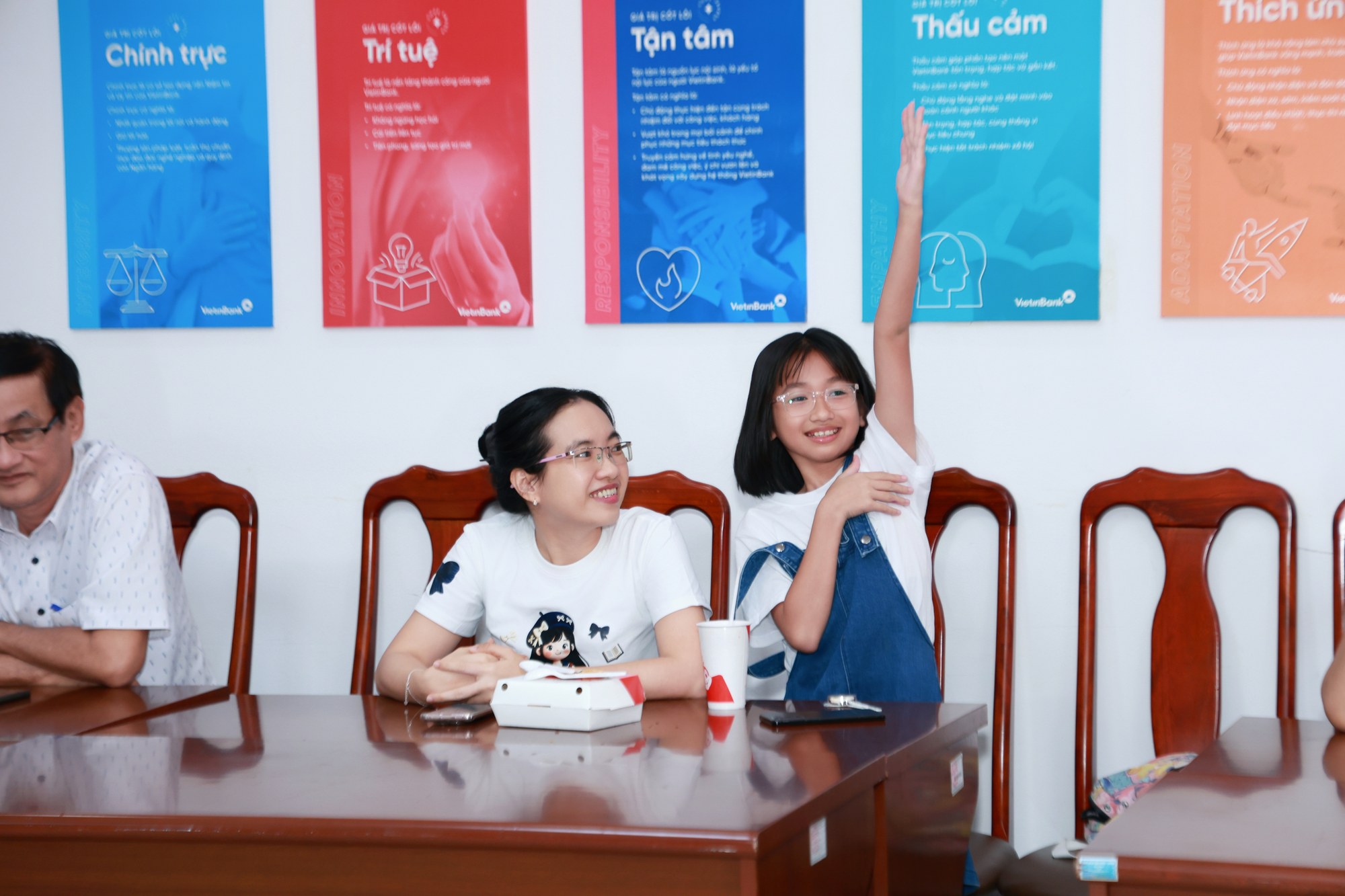 Bé gái tự tin giơ tay tương tác bên mẹ trước bảng Giá trị cốt lõi VietinBank